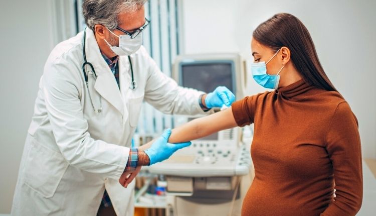 طبيب يعطي تطعيم الانفلونزا للحامل في ذراعها 