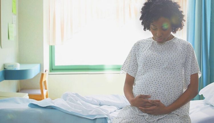 سيدة حامل تجلس على سرير في المستشفى تتسأل عن سدادة الرحم