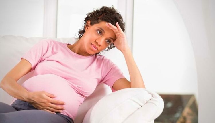 سيدة تجلس على الأريكة وتعاني من الصداع أثناء الحمل 