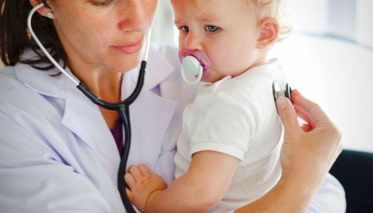 طبيبة تسمع ظهر صغير بالسماعة لاصتابته بالارتجاع الصامت عند الرضع