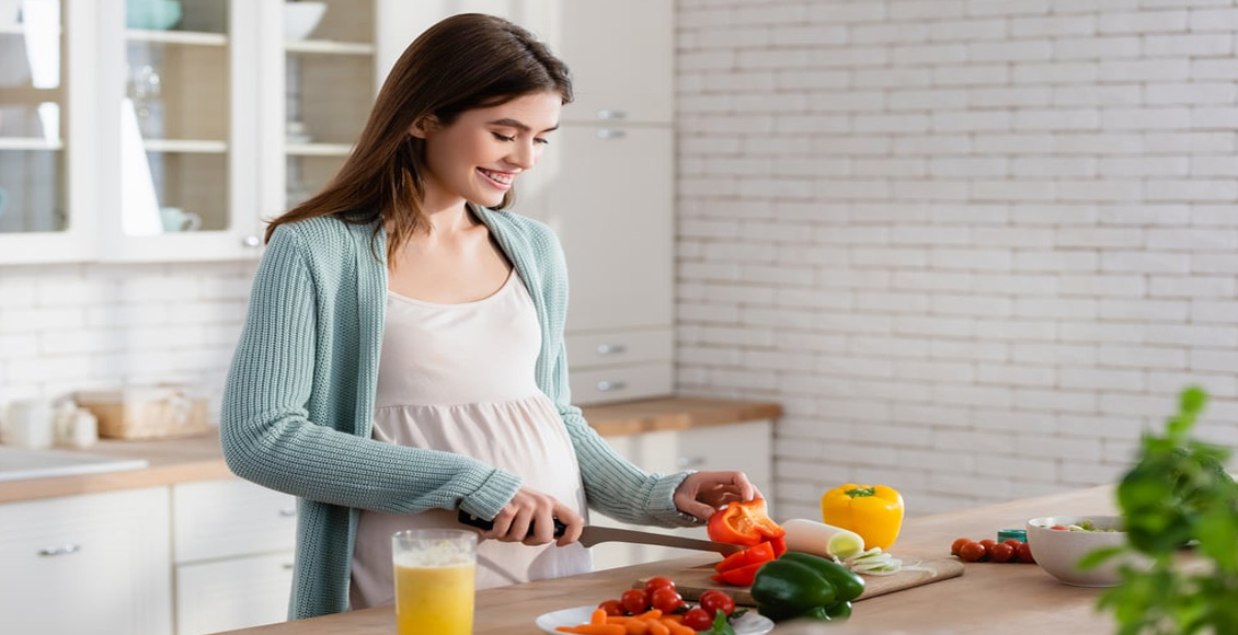 ما هو سبب عدم زيادة وزن الحامل؟ سيدة حامل تعد بعض الخضراوات وتصنع العصائر على طاولة المطبخ