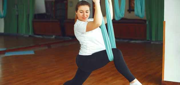 نصائح لتقليل ألم البواسير في الحمل؛ امرأة تقوم بتمارين رياضية في صالة ذات ارضية خشبية